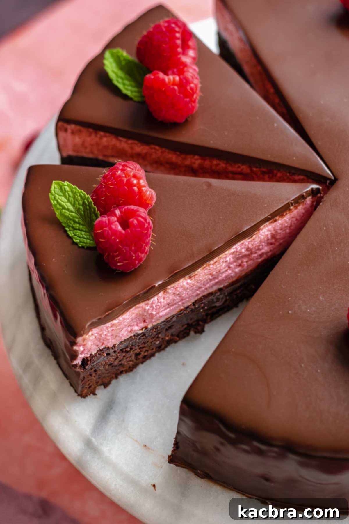 Close-up slice of raspberry mousse cake, revealing the distinct layers of brownie, mousse, and ganache.