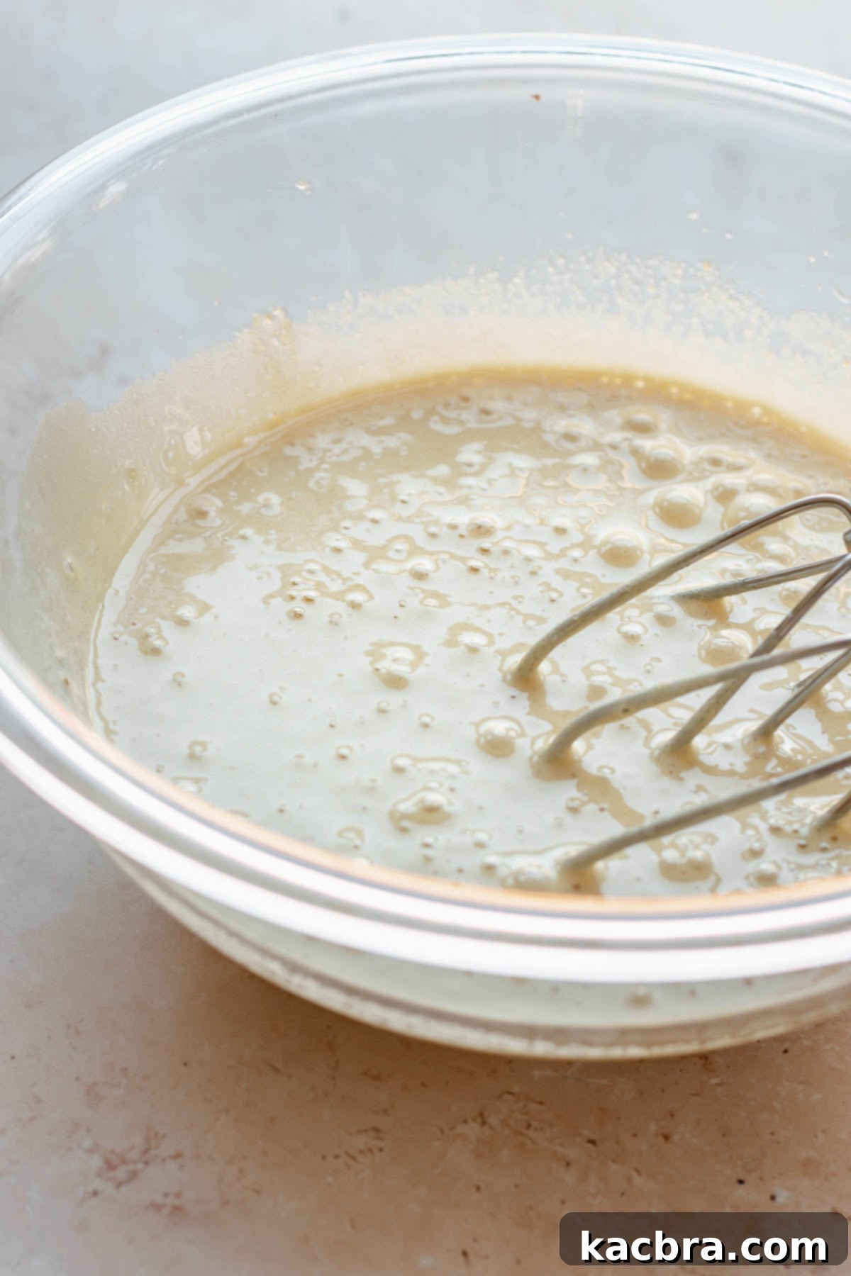 Eggs whisked in a bowl with beaters resting on the side, showing frothy texture.