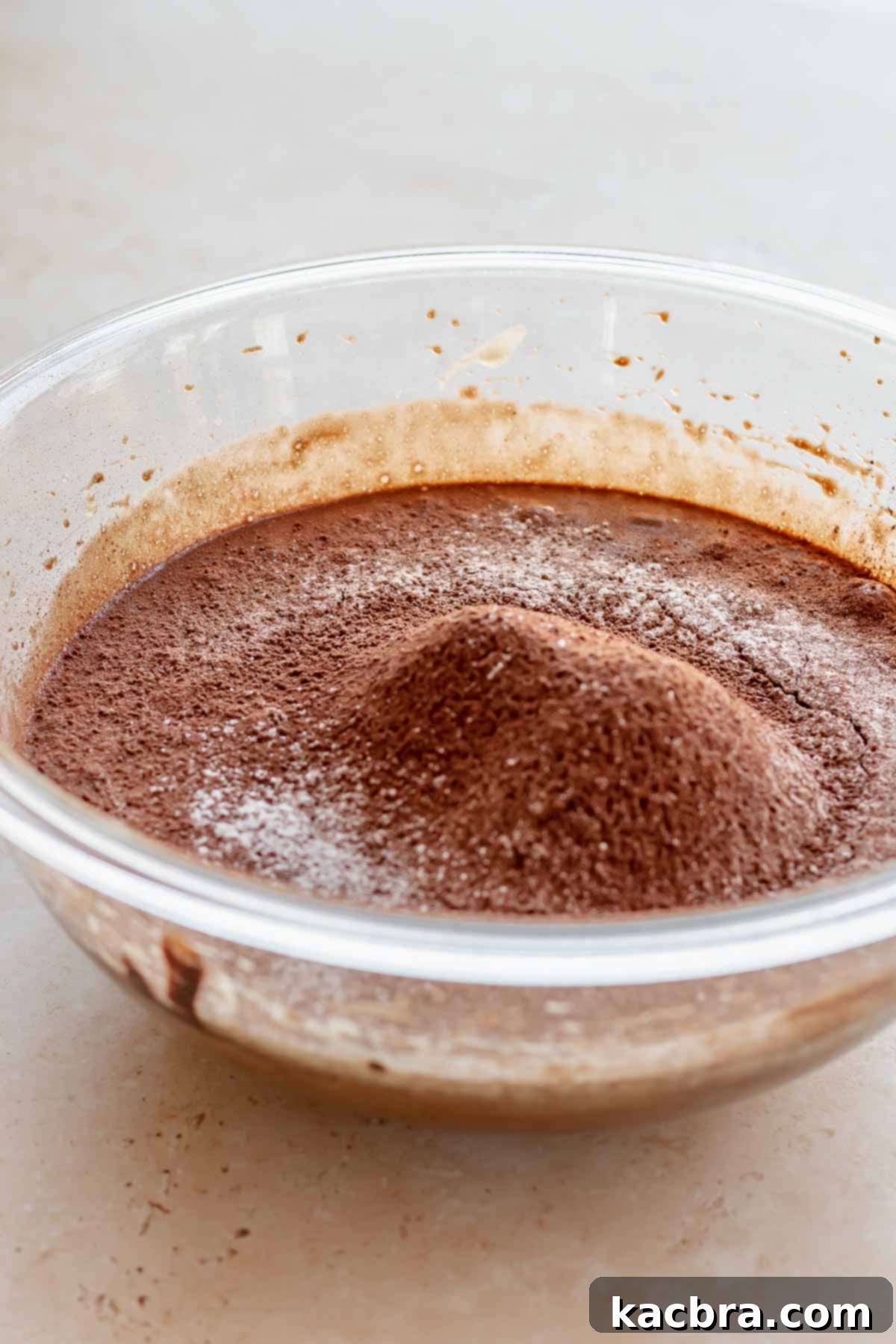 Sifted dry ingredients (flour, cocoa, salt) resting on top of wet ingredients in a bowl.