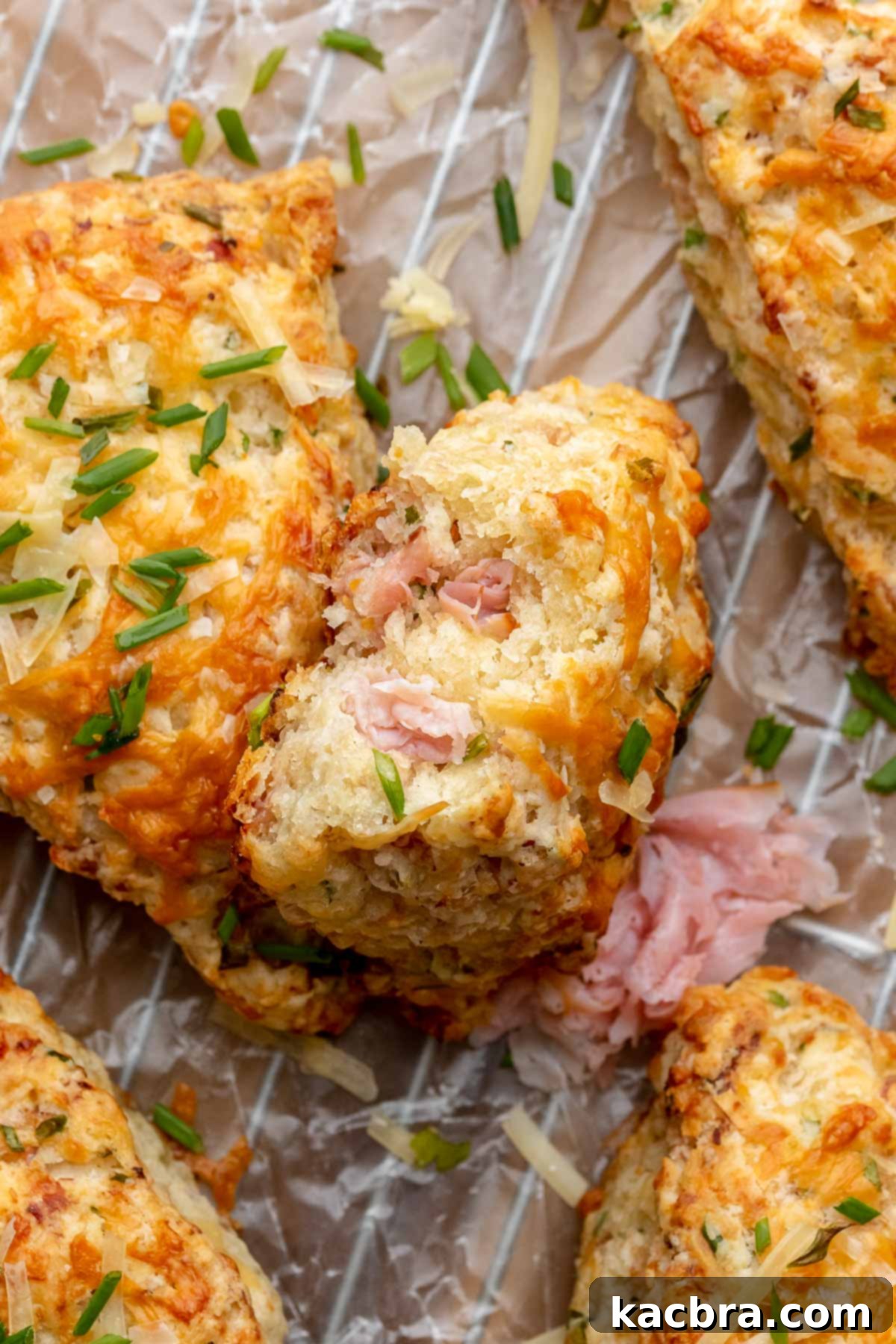 A tempting stack of homemade ham and cheese scones, showcasing their golden-brown crust and flavorful fillings. A bite has been taken from the top scone, revealing the soft, cheesy interior.