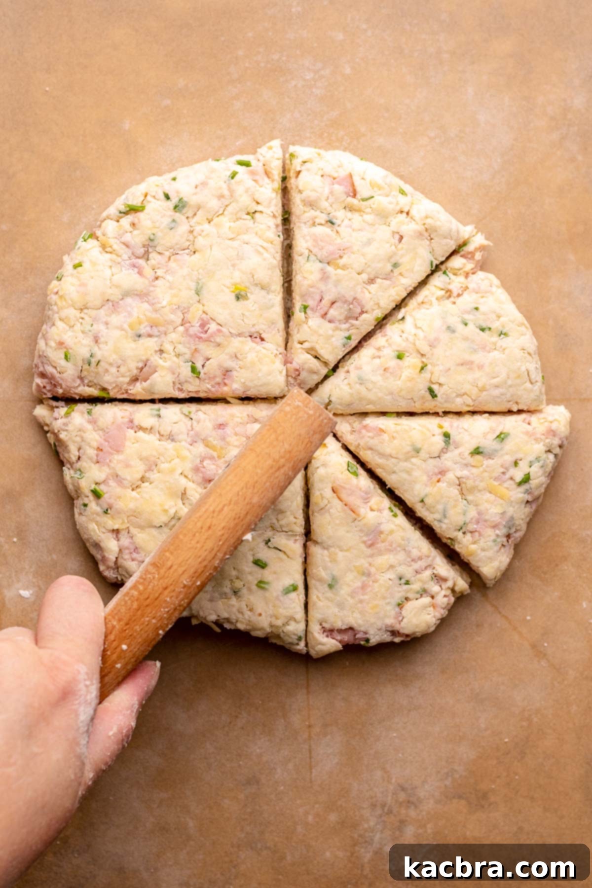 A circle of scone dough being carefully cut into eight equal slices using a sharp knife. The image illustrates the traditional method for shaping scones into wedges.