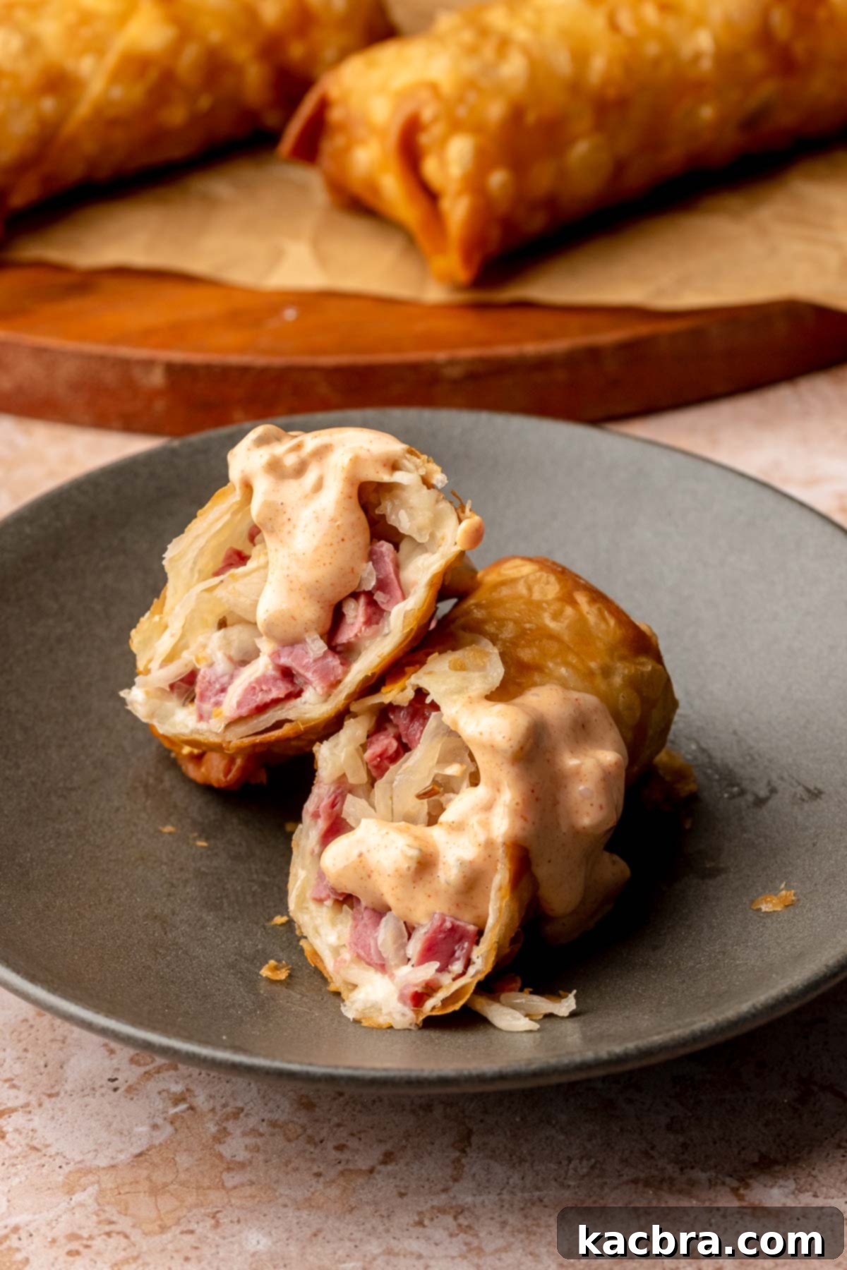 Reuben Spring Rolls 14 Reuben egg rolls cut on a plate with thousand island dip drizzled onto it